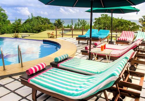 a group of lawn chairs with umbrellas next to a swimming pool at Hotel Panorama in Unawatuna
