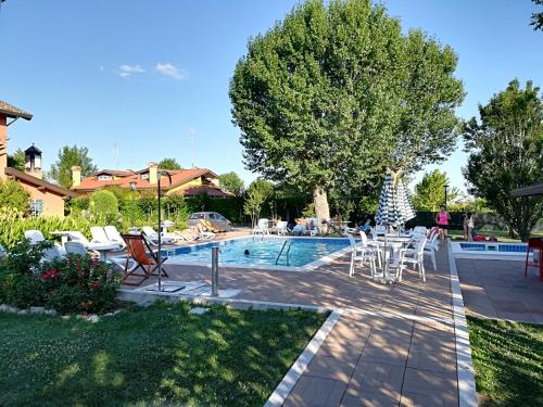 a swimming pool with white chairs and a table at Isola Di Wight in San Michele al Tagliamento