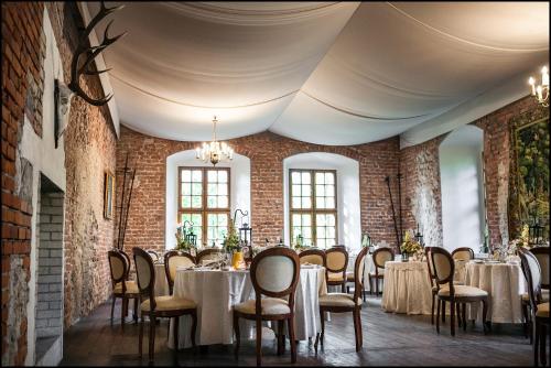 a dining room with tables and chairs and brick walls at Zamek Korzkiew in Korzkiew