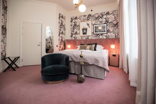 a bedroom with a bed and a green chair at The Vault Hotel, WorldHotels Crafted in Helsingborg