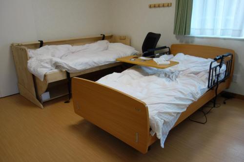 2 Einzelbetten in einem Zimmer mit einem Schreibtisch in der Unterkunft Taira no Yu in Kusatsu