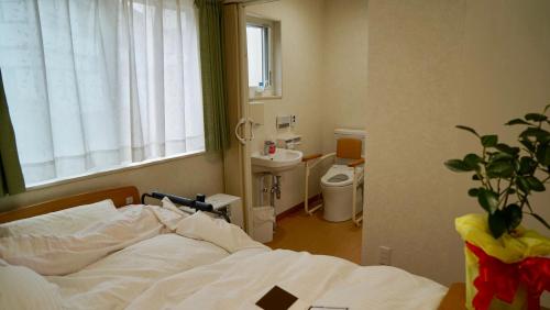 a bedroom with a bed and a toilet and a window at Taira no Yu in Kusatsu