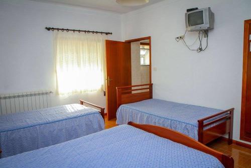 a room with two beds and a tv on the wall at Hospedaria Santa Cruz in Seia