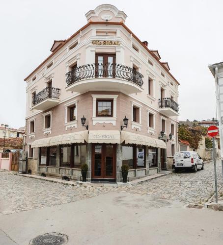 a large white building with a balcony on a street at Hotel Vila Sigal Korce in Korçë
