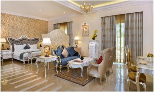a living room with a bed and a couch and chairs at Indana Palace Jaipur in Jaipur