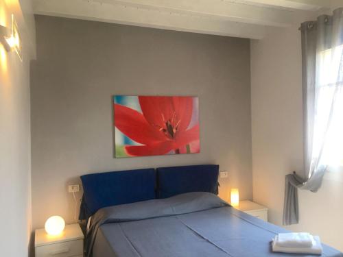 ペスキエーラ・デル・ガルダにあるComfortable apartment with terrace or balcony near Peschieraのベッドルーム1室(ベッド1台付)が備わります。壁には赤い花の絵が描かれています。