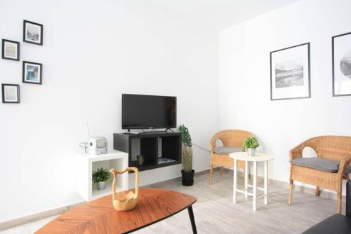 ein Wohnzimmer mit einem TV, 2 Stühlen und einem Tisch in der Unterkunft Apartamento entero 4HB centro Salamanca by Batuecas in Salamanca