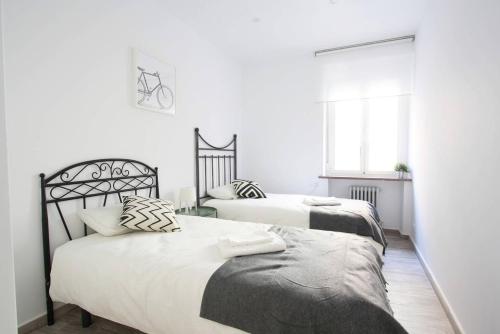 2 Betten in einem Schlafzimmer mit weißen Wänden in der Unterkunft Apartamento entero 4HB centro Salamanca by Batuecas in Salamanca