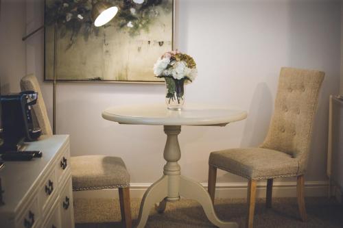 a table with a vase of flowers and two chairs at Cricket Field House in Salisbury