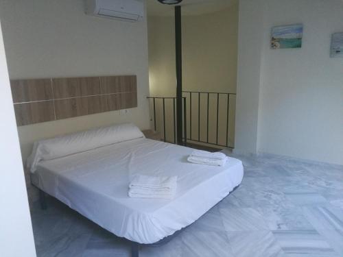 マラガにあるApartamentos Edificio Vicenteのベッドルーム1室(白いベッド1台、タオル2枚付)