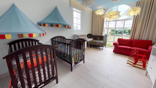 a nursery with two baby cribs and a red couch at Bahia Principe Fantasia Punta Cana - All Inclusive in Punta Cana