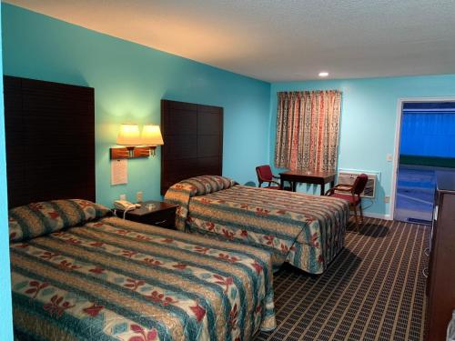 a hotel room with two beds and a table at Scottish Inn - Clanton in Clanton