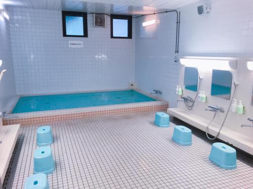 a bathroom with a swimming pool and blue stools at Kagoshima Daiichi Hotel Kishaba in Kagoshima