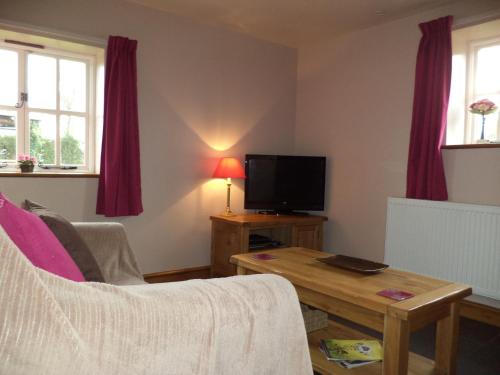 a living room with a couch and a tv and a table at Lapwing Cottage in Stoke on Trent