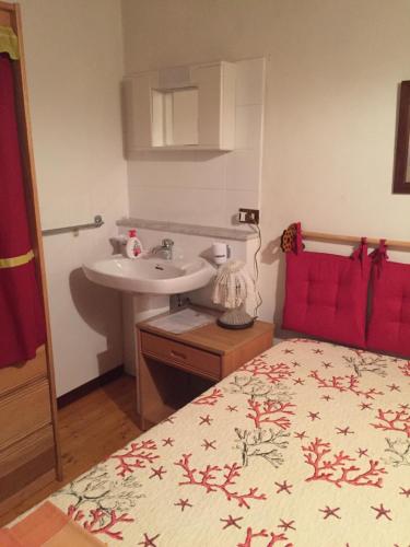 a bathroom with a sink and a bed with a red bedspread at Trifoglietto Casavacanza in Ragalna