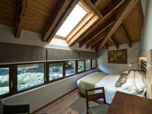 een slaapkamer met een bed en een bos ramen bij Hotel Rural Las Montañas de Pumar in Besullo