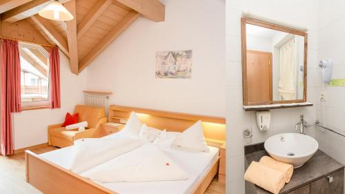 a bedroom with a white bed and a sink at Alpine Life Hotel Anabel in Cadipietra