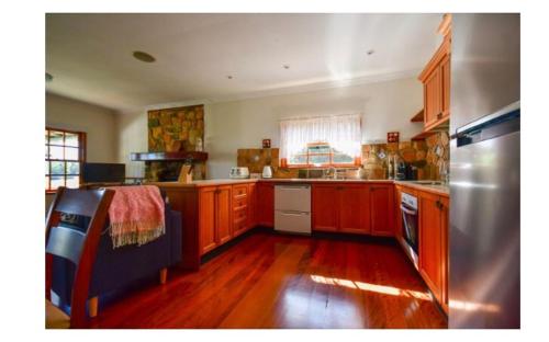 a large kitchen with wooden cabinets and a refrigerator at Lakefront holiday villa in Yungaburra