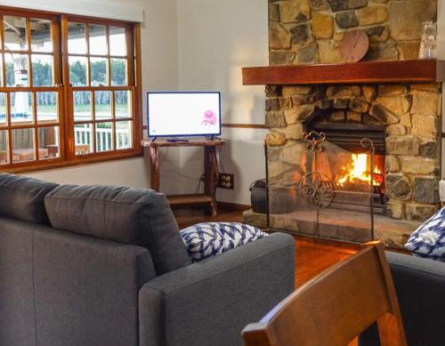 a living room with a couch and a stone fireplace at Lakefront holiday villa in Yungaburra