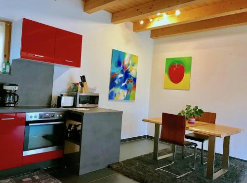 レンゲンフェルトにあるStudio Apartmentのテーブル付きのキッチン、赤いキャビネット付きのキッチン