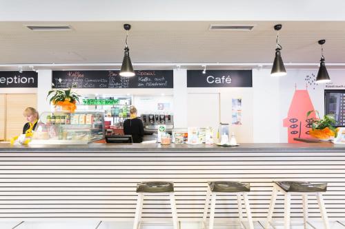 a restaurant with three stools in front of a counter at JUFA Hotel Graz City in Graz