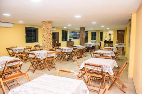 an empty restaurant with tables and chairs and a kitchen at Hotel Camocim in Camocim