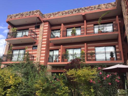 an orange apartment building with balconies and plants at Harbe Hotel in Lalībela