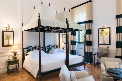 a bedroom with a canopy bed and a living room at La Posta Vecchia Hotel in Ladispoli