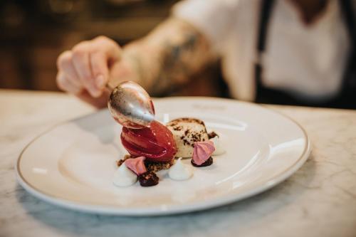 una persona está comiendo un postre en un plato en Margretetorps Gästgifvaregård, en Vejbystrand