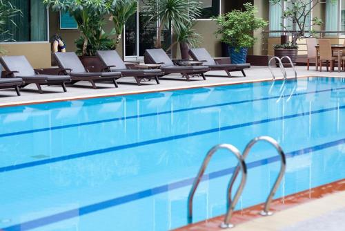 a swimming pool with lounge chairs next to a hotel at Dynasty Grande Hotel in Bangkok