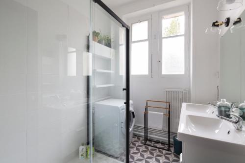 ein weißes Bad mit einer Dusche und einem Waschbecken in der Unterkunft Le Prestige by Cocoonr in Nantes