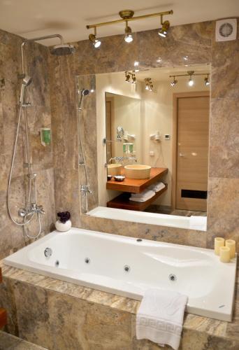 a bathroom with a tub and a shower and a sink at Hotel Capitolina City Chic in Cluj-Napoca