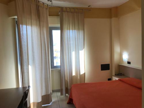 a bedroom with a red bed and a window at Hotel San Luca in Rossano