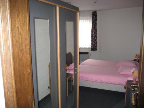 ein Schlafzimmer mit einem rosa Bett und einem Spiegel in der Unterkunft Hotel Saint-Hubert in Malmedy