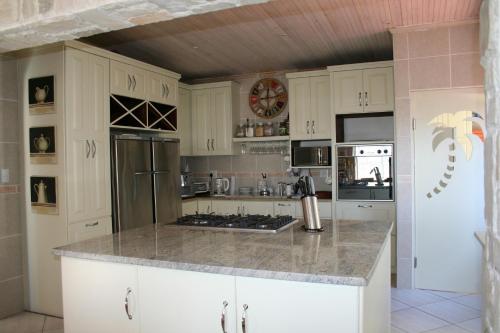 a kitchen with white cabinets and a granite counter top at High Palms (HPK) Guesthouse & kite school in Langebaan