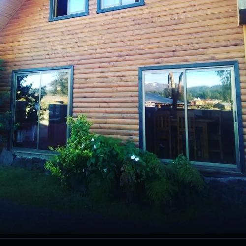 2 finestre sul lato di una casa in legno di Hostal Andalue a Puerto Fuy