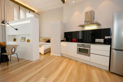 uma cozinha com armários brancos, uma mesa e uma cama em L´Aguila Suites - Turismo de Interior em Palma de Maiorca