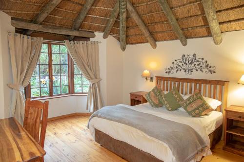 a bedroom with a bed and two windows at Coral Tree Cottages in Harkerville