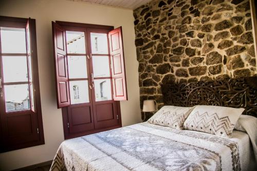 1 dormitorio con cama y pared de piedra en A casa da Igrexa, en Ribadavia