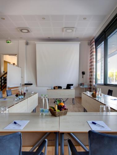 a conference room with tables and a white screen at Glostrup Park Hotel in Glostrup