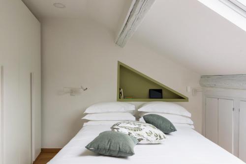un letto bianco con cuscini verdi di SPAZIO M&M Via Augusto Anfossi 10 a Milano