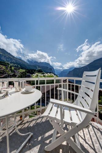 a white table and chairs on a balcony with a view at Hotel Regina in Wengen
