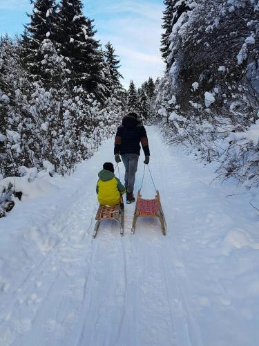 a man pulling a child on a sled in the snow at Panorama Hotel Guggenbichl - inkl Sommerkarte, einmaliger Eintritt ins Tauern Spa & bester Ausblick über Kaprun in Kaprun