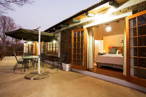 a patio with a bed and a table with an umbrella at Rivendell Trout Estate in Lydenburg