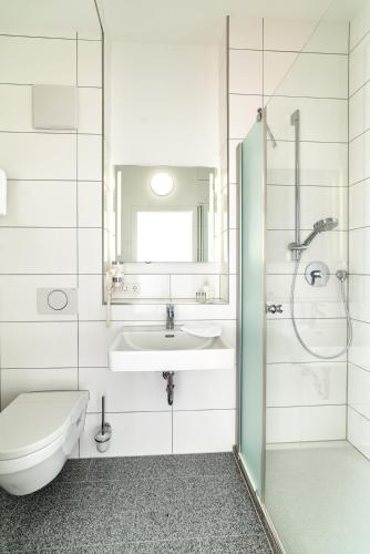 Un baño con lavabo, inodoro y ducha. en Hotel am Stadtrand, en Ostfildern