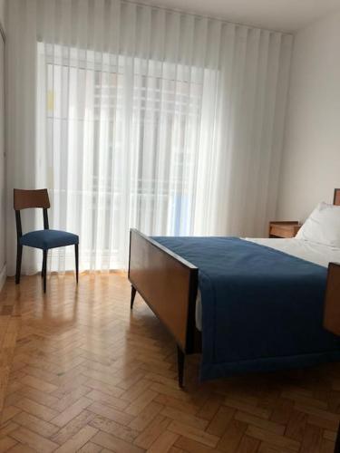 a bedroom with a bed and a chair and a window at SEA RIA - A casa dos Maria in Costa Nova