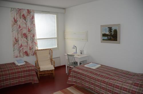 a bedroom with two beds and a desk and a window at Lomakoti Onnela in Haukipudas