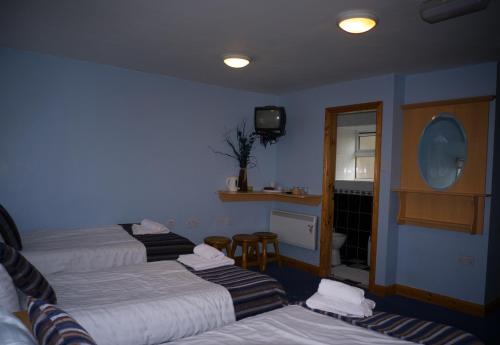 a hotel room with three beds and a television at The Dingle Pub Rooms in Dingle