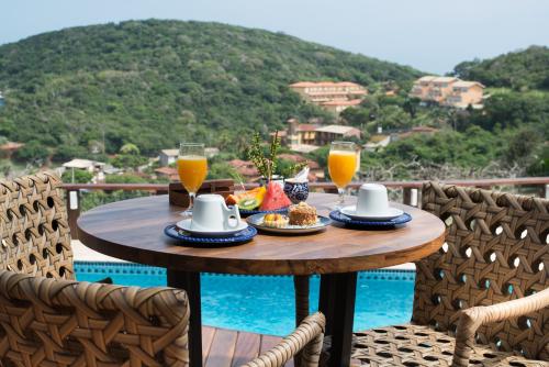 a table with two glasses of orange juice and food at Ilha Branca Exclusive Hotel in Búzios