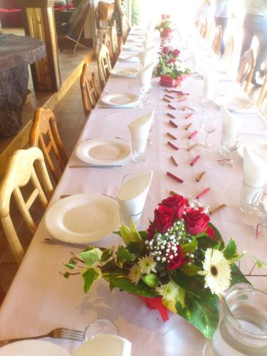 una mesa larga con platos blancos y flores. en L'Arum des Prairies, en Bras des Calumets